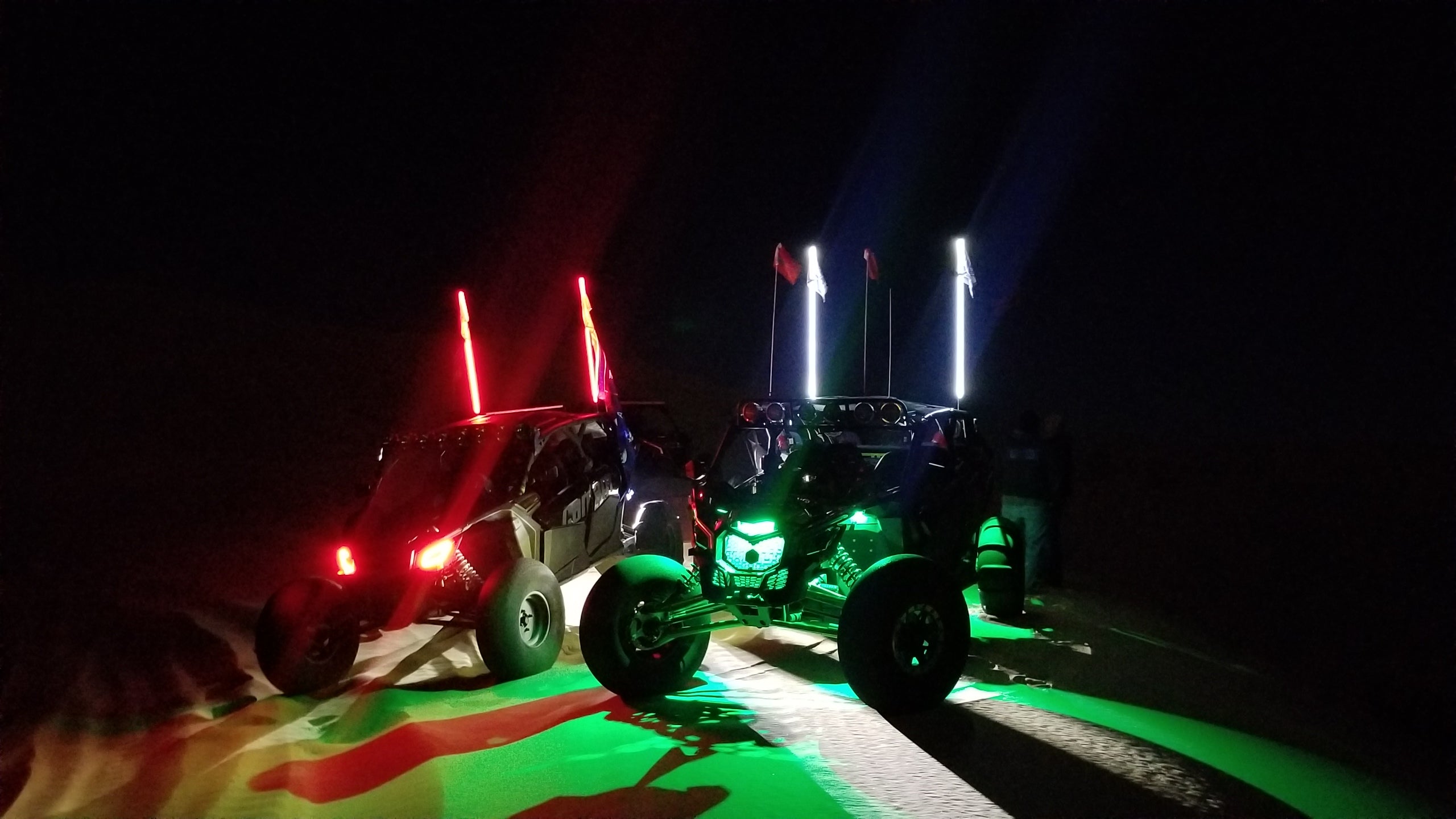 outdoor night photo of UTVs with colorful rock lights